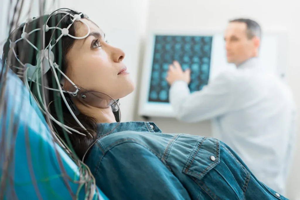 Patient undergoing a neurological test while a doctor reviews brain scans. Neurology billing services ensure accurate coding.